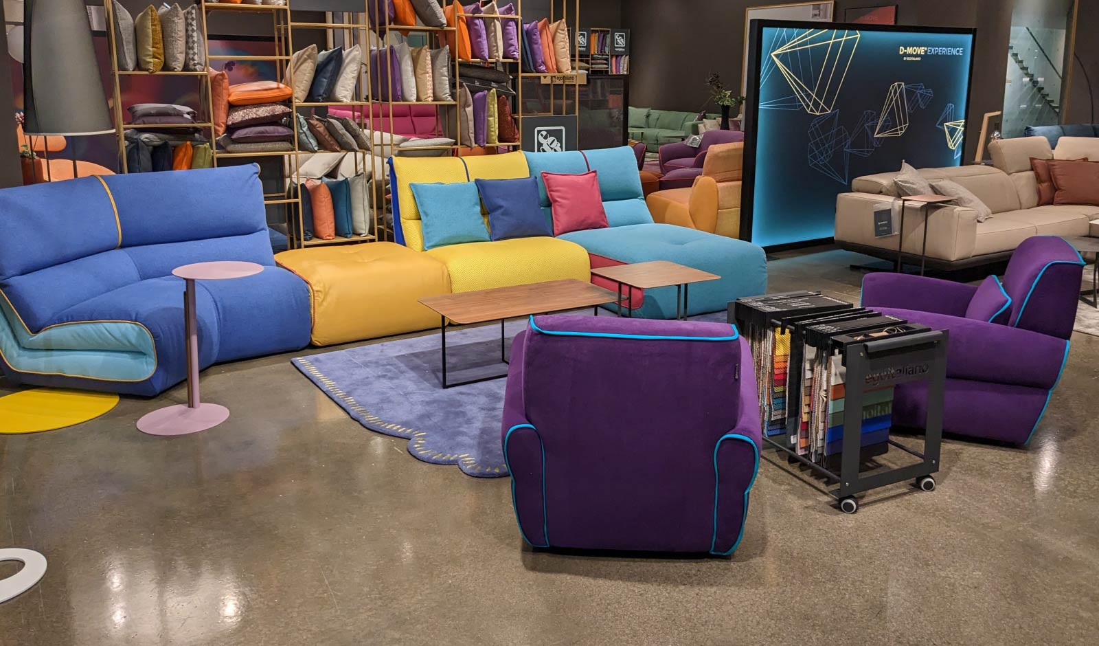 A contemporary sectional and lounge chairs in blue, aqua, yellow and purple